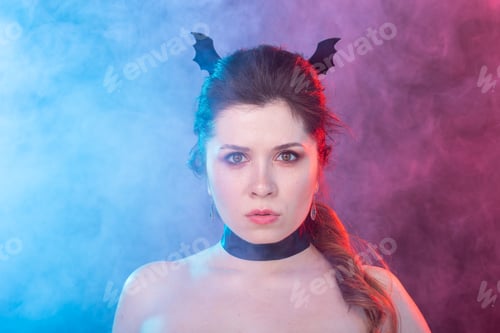 Preview: Dark fashion, halloween and people concept - gothic woman in bat ears over the dark background