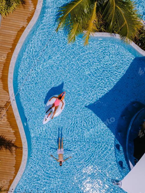 Preview: View from above at a swimming pool, couple men and women in swimming pool, drone view