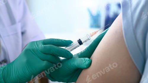 Preview: Close up view of doctor holding syringe and giving injection to woman at hospital.