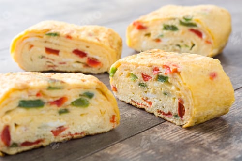 Preview: Tamagoyaki, japanese rolled omelette with vegetables, sliced on wooden table