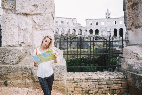 Preview: Young blonde woman 20s reading map searching routes and directions during city tour