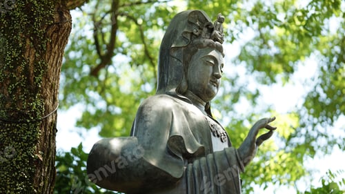 Preview: Aged Hindu goddess Devi statue stands on a lush green backdrop of trees