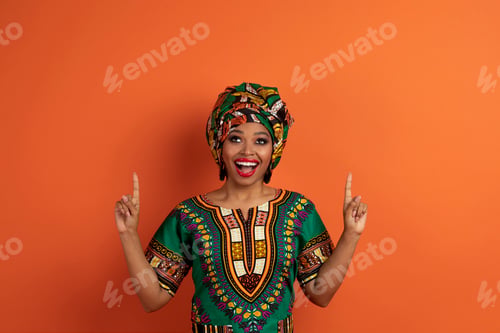 Preview: Emotional african lady pointing up at copy space
