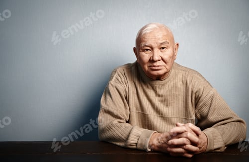 Preview: Pensive and thoughtful senior man sitting at the table