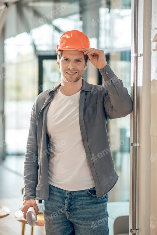 Preview: Smiling man touching protective helmet on head