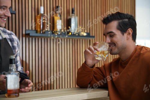 Preview: Young man with glass of whiskey in bar