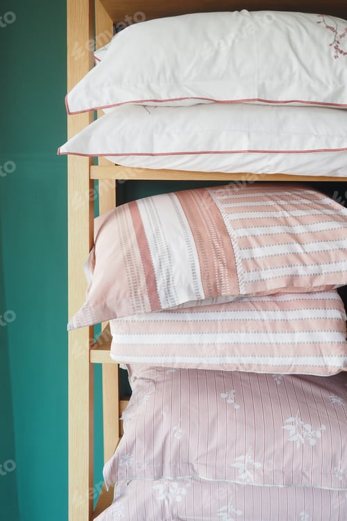 Preview: Pillows stacked on wood shelf in bedroom with linens