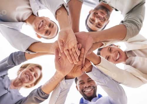 Preview: Low angle shot of a group of businesspeople joining their hands together in a huddle in an office