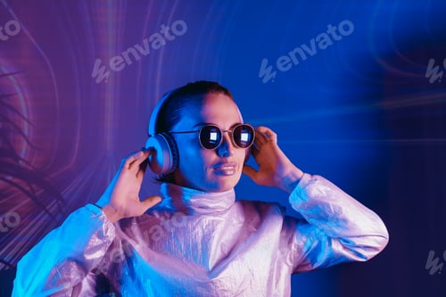 Preview: Portrait of smiling woman in sunglasses and headphones in neon light. Music lover