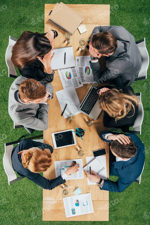 Preview: Top view of business partners having discussion at table with documents and devices in office