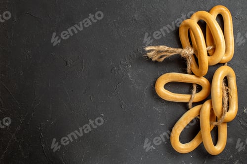Preview: Horizontal view of ring-shaped cookies with a rope tied to one another on dark background