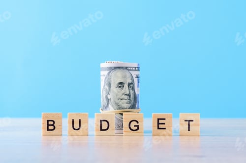 Preview: Rolled up dollar bills and word budget on a blue background.