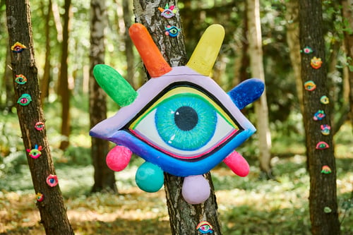 Preview: Art object of human eyes on tree trunk in green forest background
