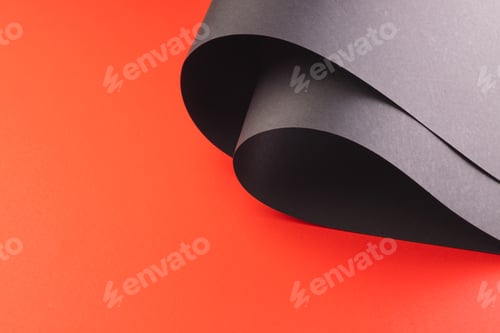 Preview: Close up of rolled up pieces of black paper with copy space on red background