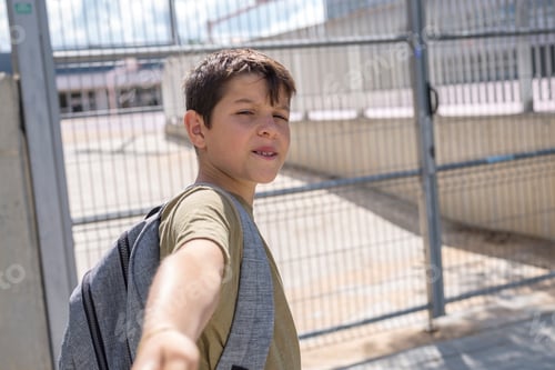 Preview: Cheerful child carrying his backpack standing in front of the school