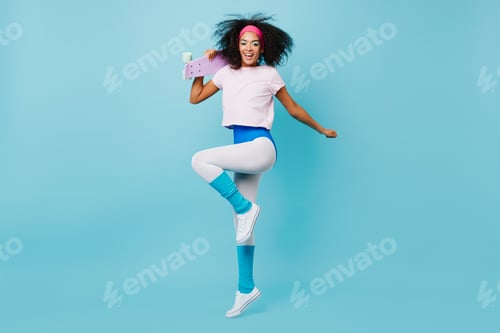 Preview: Carefree fitness woman dancing with sincere smile. Studio shot of slim african girl jumping with sk