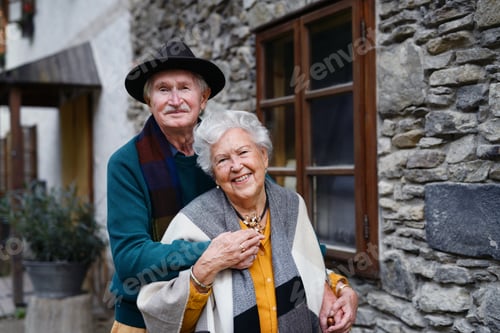 Preview: Happy senior couple posing near old countryside house.