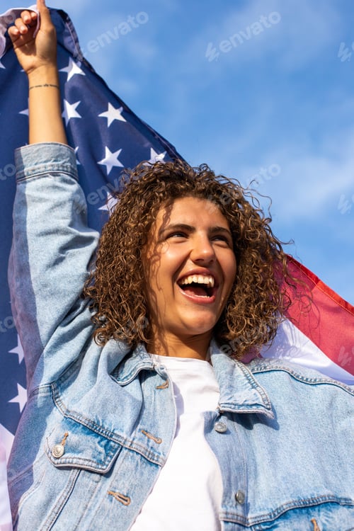Preview: Happy beautiful curly haired woman holding American flag