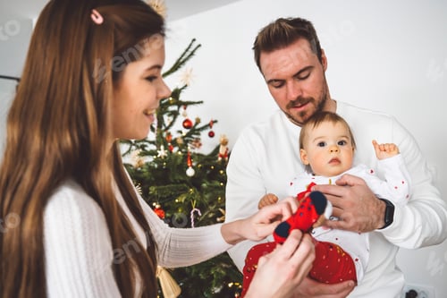 Preview: Mom putting Christmas socks on baby girl, while dad is holding her