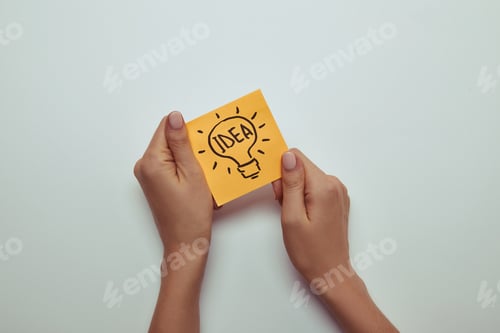Preview: cropped image of woman holding paper sticker with word idea in lightbulb