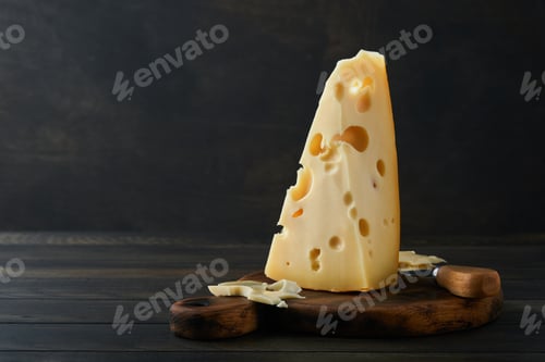 Vista previa: Cheese. Piece of cheese triangle, Swiss cheese on with basil and a knife on a serving board on dark