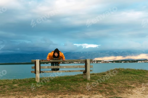 Preview: Little girl in a yellow jacket on a bench by the sea