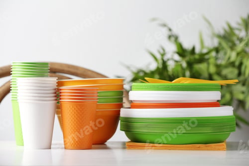 Preview: New plastic dishware on table against blurred background. Table setting