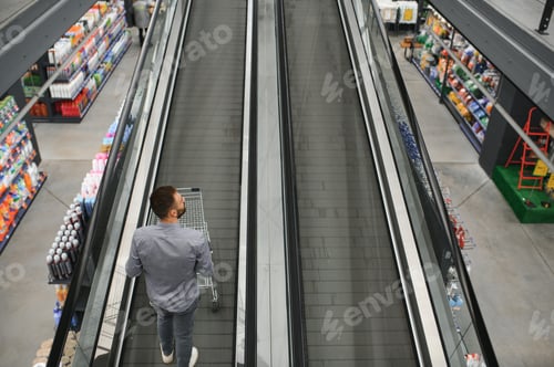 Preview: A man with a shopping cart on an escalator in a hardware store.
