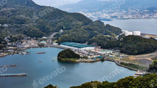 Preview: View of a coastal town with lush green hills, a bay, and industrial buildings in Sasebo, Nagasaki