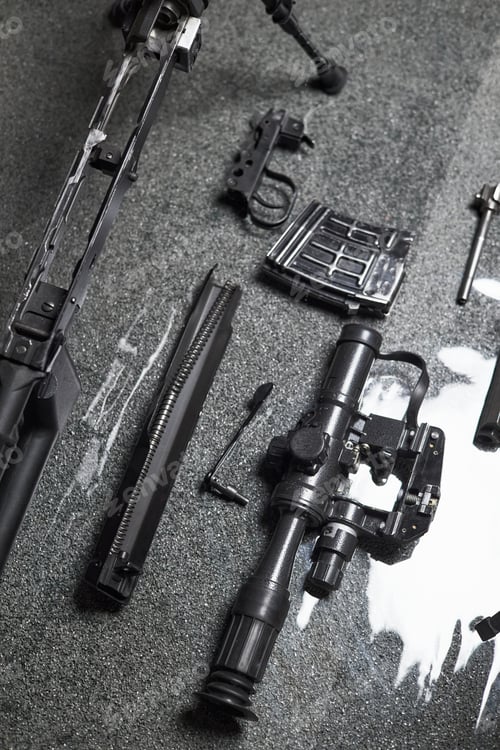 Preview: Disassembled Military Rifle with Scope and Magazine Lying on Reflective Surface