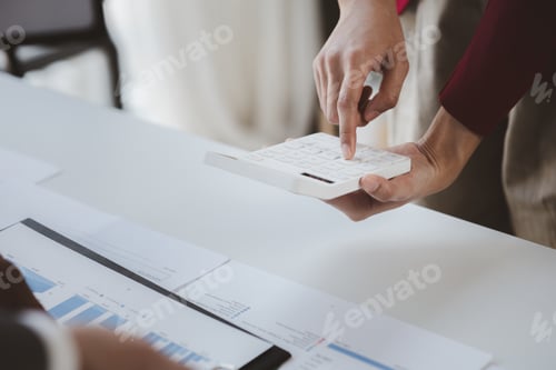 Preview: Businessman using a calculator to calculate numbers on a company's financial documents.