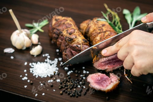 Preview: slicing organic roast beef roll on wood table with ingredients