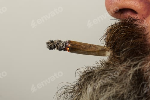 Preview: man with beard smoking a joint of marijuana
