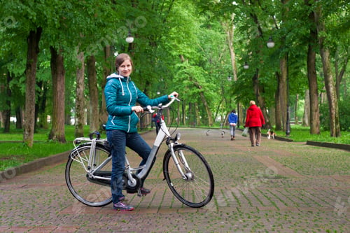 Preview: Young woman with a bicycle in the park