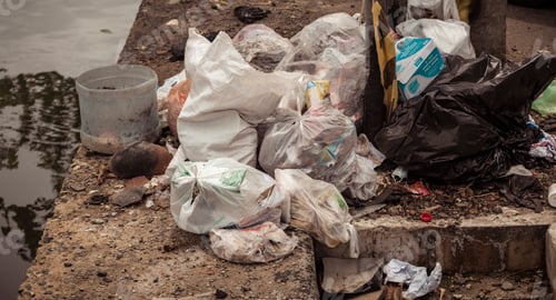 Preview: Pile of polythene bags and trash in the streets near a lake.