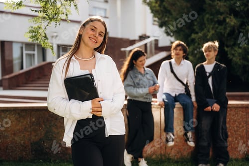 Preview: Girl is standing in front of her friends. Group of students are near university together