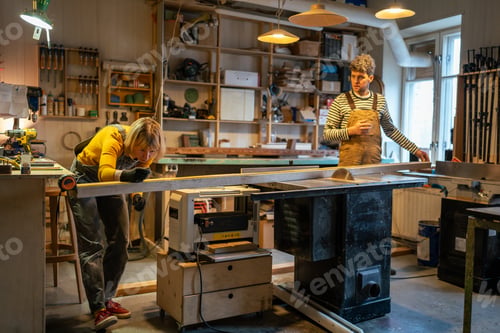 Preview: Family carpenters use table saw to cut wooden beams in workshop. Hands on teamwork, small business