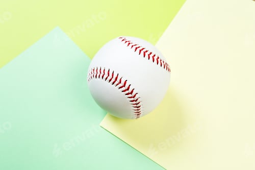 Vorschau: Baseball, der auf farbigen Papieroberflächen in einer einfachen Innenumgebung ruht