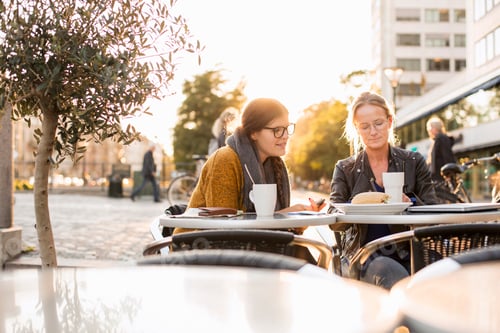 Preview: Businesswomen discussing on table at sidewalk cafe