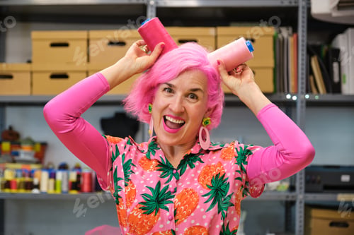 Preview: Dressmaker with pink hair making funny faces with sewing thread reels.
