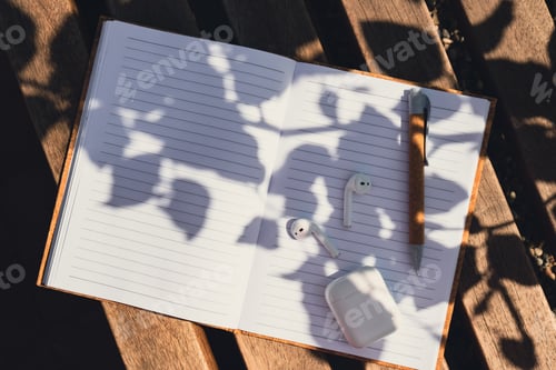 Preview: Paper notebook with wireless headphones. Mockup Coffee break. Audio healing, sound therapy wellness