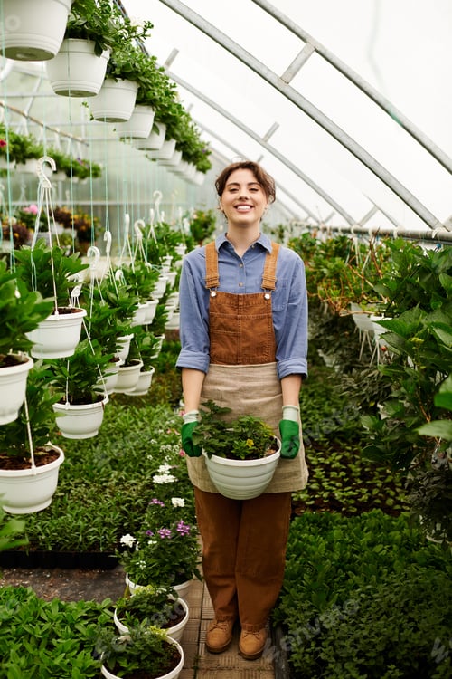 Preview: Joyful gardener nurturing vibrant plants in a thriving greenhouse environment