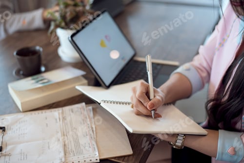 Preview: Close up. Business woman taking notes in notebook on desk at office.
