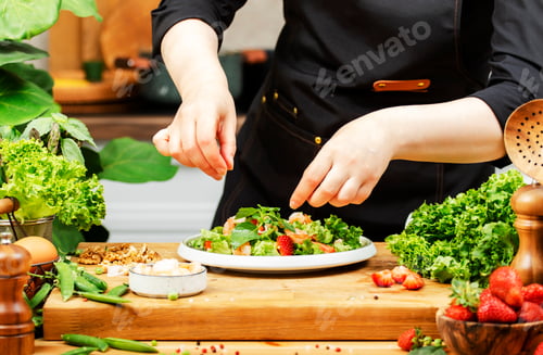 Preview: Private chef carefully prepares vibrant salad using fresh vegetables, herbs, and strawberries