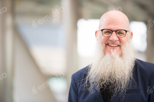 Preview: Face of happy mature bearded bald businessman smiling in the city outdoors