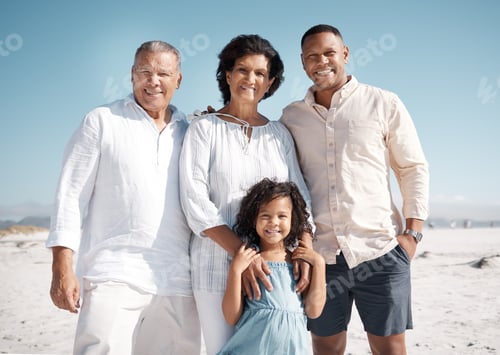 Preview: Smiling mixed race family standing together on a beach. Hispanic grandmother and grandfather bondin