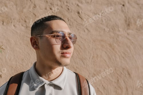 Preview: Portrait of a young arab man wearing sunglasses, t-shirt and leather backpack