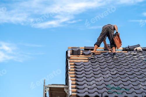 Preview: new roof of a family house, a worker builds a roof made of ceramic tiles