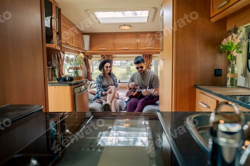 Preview: Young man playing guitar while sitting next to his girlfriend