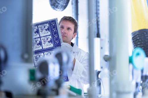 Preview: Worker inspecting circuit board by processing plant in circuit board factory